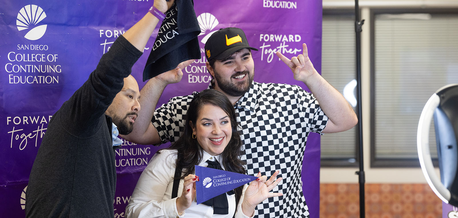 Three people taking a picture with SDCCE swag. 