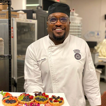 Man in chefs coat holding a plate of food