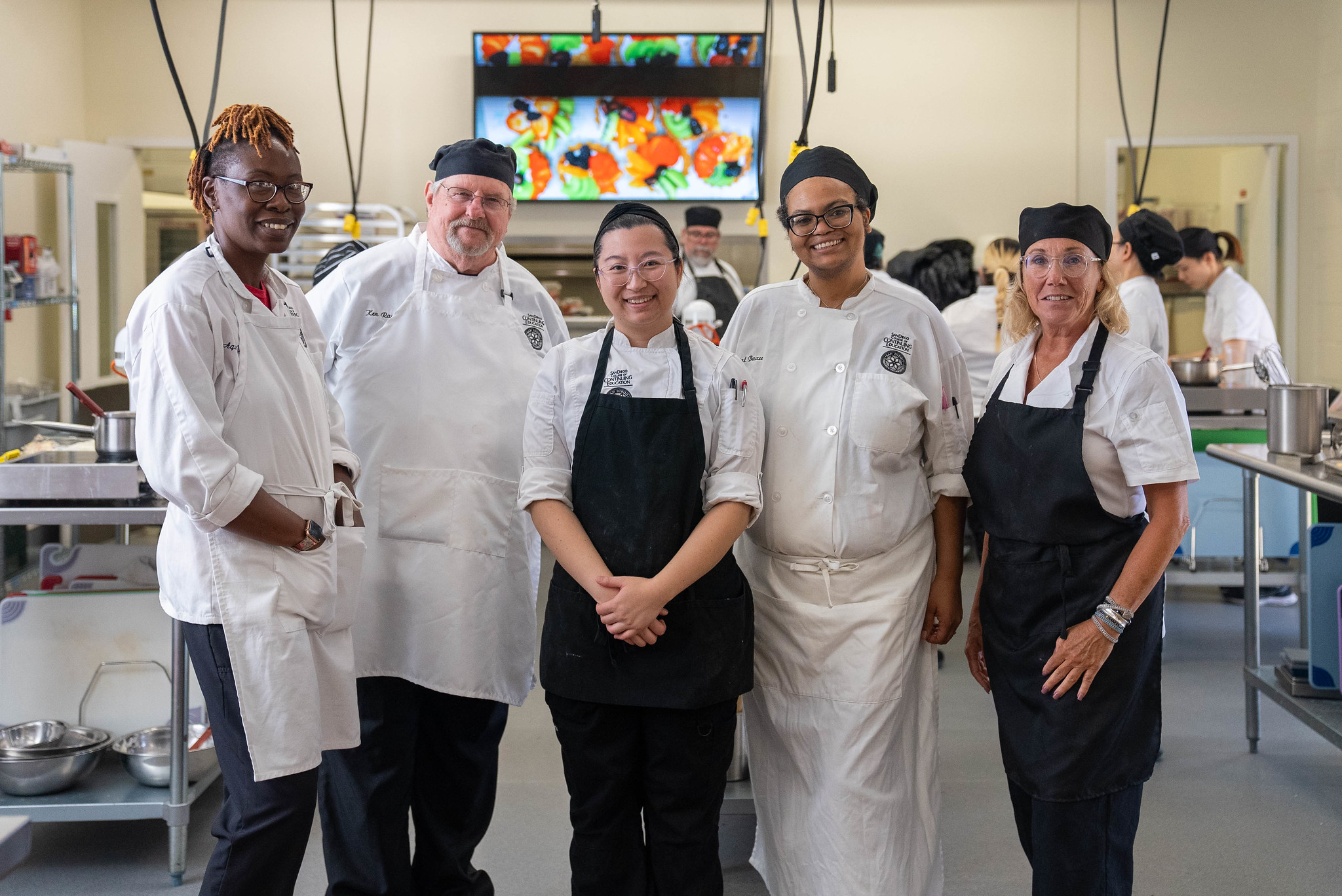 Culinary students standing in the kitchen class in their chef coats